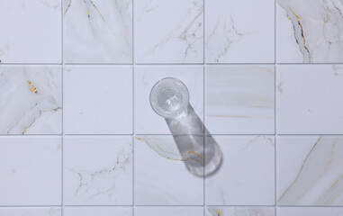 Retro crystal shot glass with shadow on tile. Aesthetics, trendy still life, minimalism. Top view
