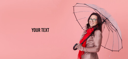 Portrait of smiling beautiful woman in glasses holding umbrella and talking on phone on a pink background. Copy space