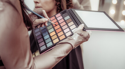 Make-up artist holding make-up palette and brush in beauty salon