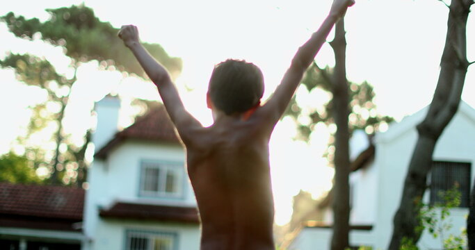 Confident Child Celebrating Success By Raising Fists In The Air. Boy Raises Arms In The Sky In Celebration