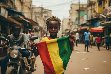 Un garçon guinéen tenant le drapeau de la Guinée dans les rues de Bamako - obrazy, fototapety, plakaty