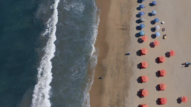 Aerial video looking down on a beach full of beach chairs and umbrellas