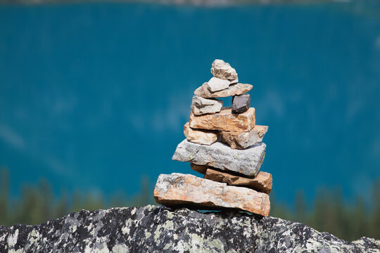 Close up of rock cairn sitting on a rock with blue lake in background; Field british columbia canada