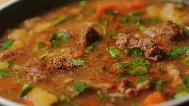 Hungarian goulash soup cooking close-up in pot, chef cook traditional polish or zech soup in restaurant. 