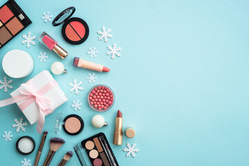 Winter cosmetic with present box and holiday decorations on blue. Christmas sale and gift concept. Flat lay with copy space.