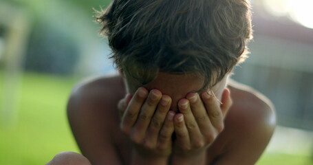 Child covering face with shame. Boy hinding face with hands