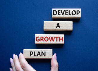 Develop a growth mindset symbol. Wooden blocks with words Develop a growth mindset. Beautiful deep blue background. Businessma hand. Business concept. Copy space