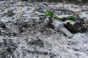 black burnt field, green bottle on burnt field, consequences of fire
