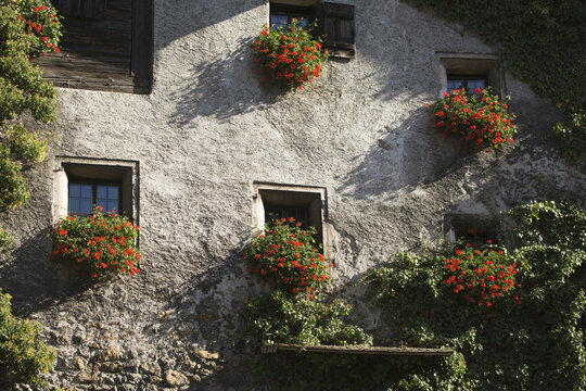 Close Up Of A Stone Building With Colourful Flowers In Window Boxes; Rattenburg, Austria