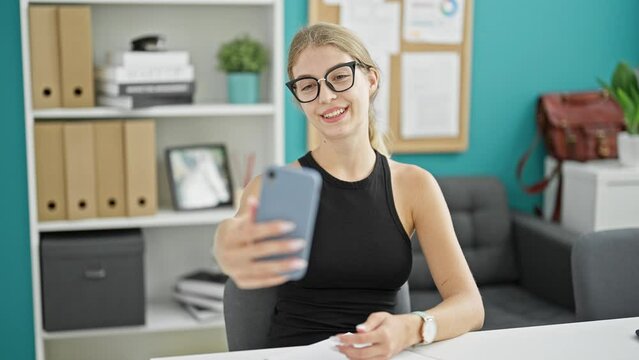 Young blonde woman business worker make selfie by smartphone smiling at the office