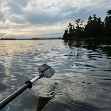 A Paddle Rowing On A Tranquil Lake At Sunset; Ontario, Canada