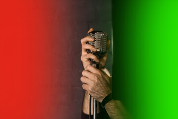 Hands Man Holding Professional Silver Retro Microphone Karaoke Singing Equipment On Red And Green Background