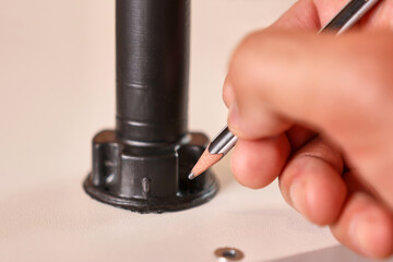 Holes for fastening the furniture leg are marked with a pencil. Assembling cabinet furniture.