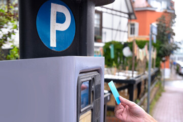 man pays with bank credit card for time of parking car in street parking meter with solar panels,...