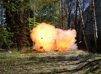 The moment of explosion. Fire from a large explosion between green trees
