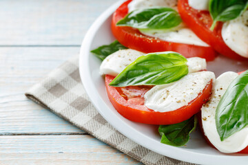 Delicious Caprese Salad with ripe tomatoes and mozzarella cheese with fresh basil leaves. Italian food. Close up