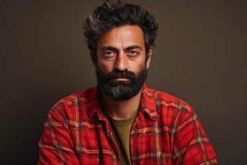 Portrait of a bearded Indian man in a red plaid shirt.