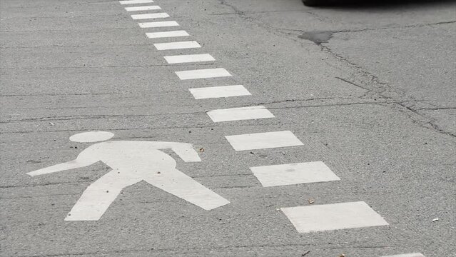 stencil outline illustration of person walking in white on cement pavement road street beside dotted line with cars vehicles traffic passing