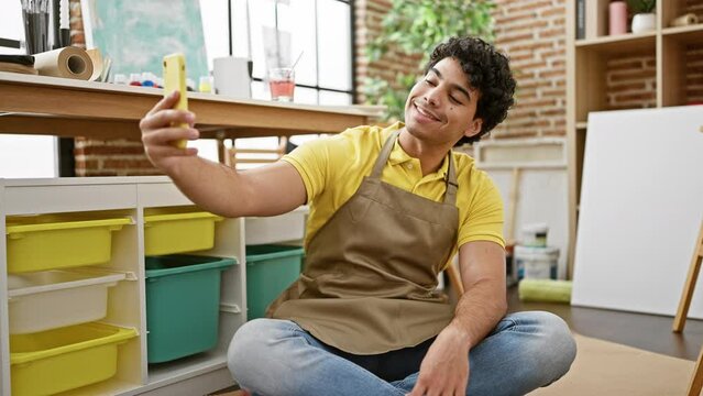 Young latin man artist smiling confident make selfie by smartphone at art studio