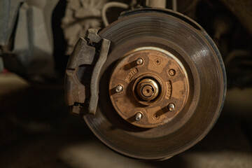Close-up of a brake disc and pad on a car. Repairing and changing brakes on a car in a garage. A...