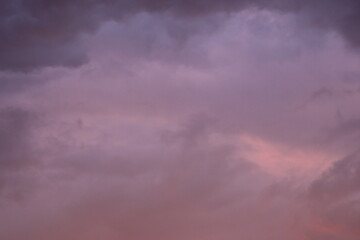 pink blue rainy clouds against the background of the winter sky illuminated by the rays of the sun,...