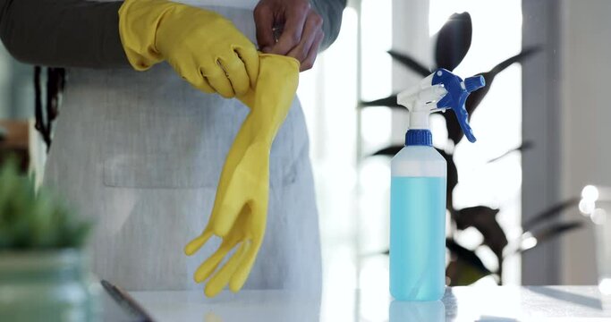Person, hands and gloves in housekeeping, cleaning or hygiene with spray bottle or detergent on table. Closeup of maid, cleaner or domestic getting ready for disinfection, bacteria or germ removal