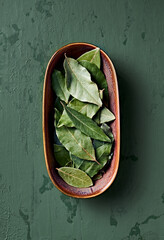 Dried bay leaves in a rustic ceramic dish. Top view. Natural, healthy spices
