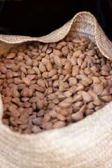 Close-up of delicious raw Marcona almonds in shell in an esparto basket.
