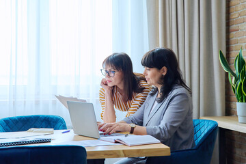 Two mature business women colleagues employees working together in office