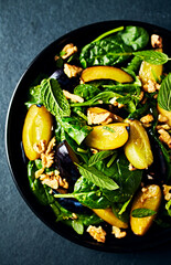 Autumnal plums and spinach salad with toasted walnuts, honey and mint leaves. Top view