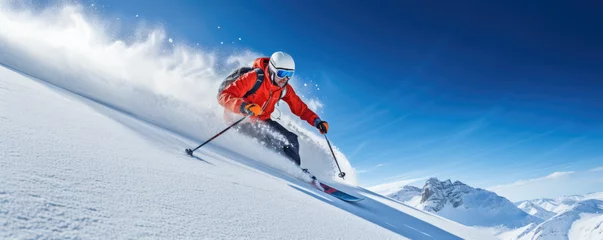 Fototapeten Skier carving down a powdery slope against a clear blue sky © thejokercze