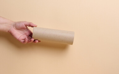 A woman's hand holds a brown paper tube from paper towels