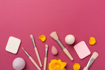 Makeup brushes and sponges on color background, top view
