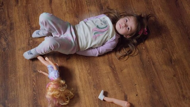 Little girl lies on the floor and cries upset about the broken doll