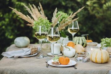 Simple craft elements, pumpkins as decoration, candles. Lunch outdoors in the garden. Cozy dinner table decor for an autumn event, countryside party, thanksgiving dinner or wedding.