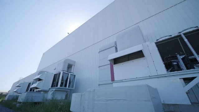 Large ventilation pipes on facade of commercial building. Outdoor split air conditioner units mounted on industrial building facade. Air conditioning system assembled on side of building