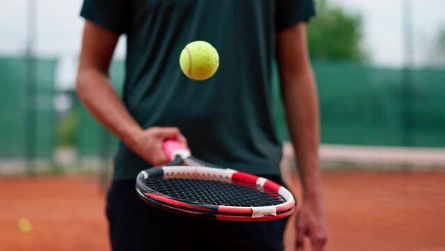 close-up young tennis player trainer hitting the ball with a racket on the tennis court preparing for the competition sports lifestyle