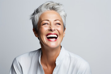 A closeup photo portrait of a beautiful elderly senior model woman with grey hair laughing and smiling with clean teeth. used for a dental ad. isolated on white background.