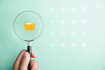 Conceptual image of a hand holding a magnifying glass, conducting a thorough examination of documents for quality assurance and ISO compliance. Concept of accurate work and information management.