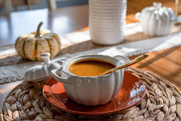 Closeup of a bowl of pumpkin soup on a dining room table
