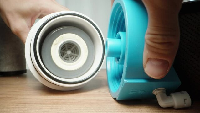 I unscrew the blue lid of the cartridge housing for the water filter, close-up.