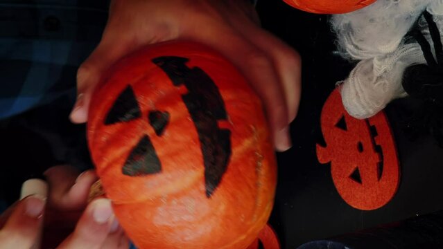 Happy cheerful man preparing for Halloween, painting pumpkin face.Vertical video