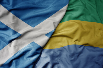 big waving national colorful flag of scotland and national flag of gabon .