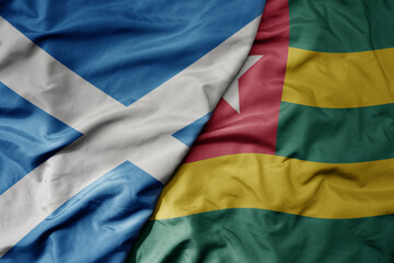 big waving national colorful flag of scotland and national flag of togo .