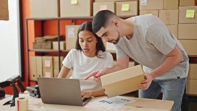 Man and woman working together, two office workers reading package information on laptop in the warehouse