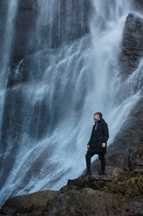 male tourist looking at waterfall in mountains outdoors © goami
