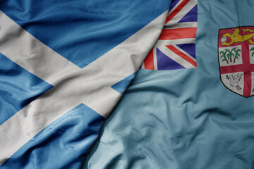 big waving national colorful flag of scotland and national flag of Fiji .