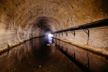 Fototapeta na wymiar Underground flooded vaulted urban sewer tunnel with dirty sewage