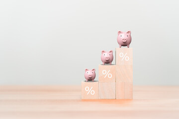 Piggy bank on wooden cube blocks with percentage sign on the table. Business, saving, investment,...
