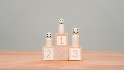 Wooden doll standing on the podium 1st, 2nd, 3rd positions of wooden cube block. Business concept of strategy, ranking, competition and committed.